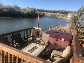 Firepit table and lounge with hot tub and river.