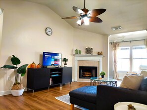 Spacious and modern living room with natural light, large smart TV, and books