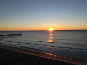Breathtaking ocean sunrise with warm colors and a glowing distant pier.








