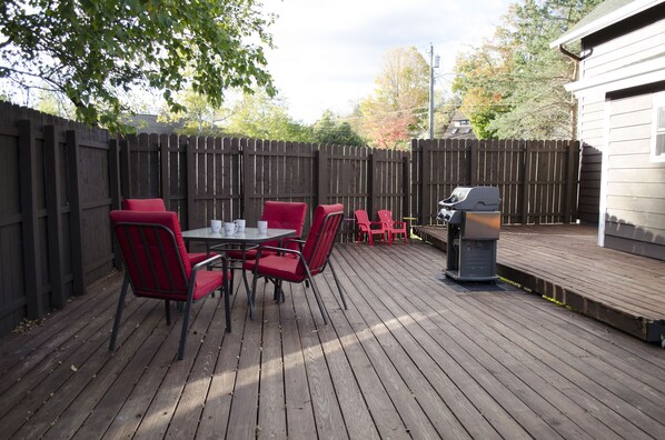 Fenced in yard with large deck and Weber grill

