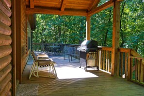 View of covered portion of deck with seating and gas grill