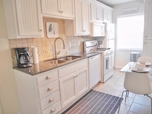 The kitchen is complete with everything from cookware to plates and a coffee maker 