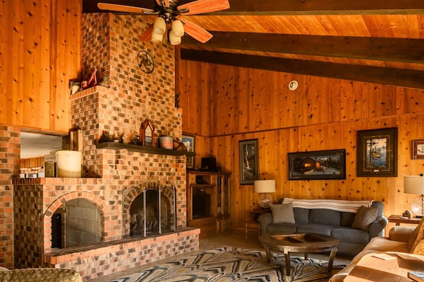 A massive fireplace and vaulted ceiling highlights the living room