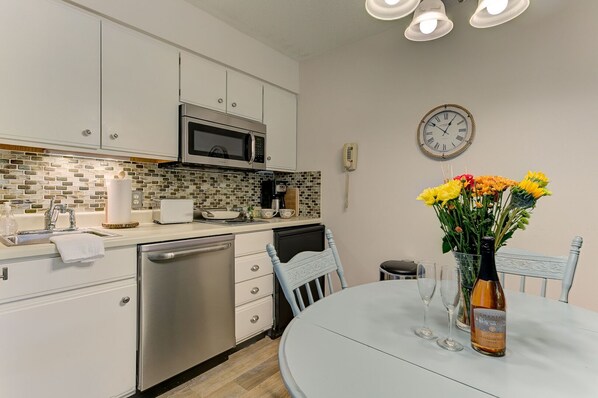 The unit is equipped with a full kitchen, excluding an oven, and features a dining table.
