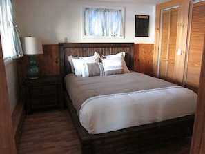 Downstairs bedroom with queen size bed, nightstand, and lake view