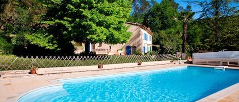 La piscine avec la bastide dans le fond
