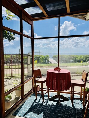 Private screened in patio seating area with ceiling fan, looking out to the sea.
