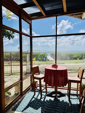 Private screened in patio seating area with ceiling fan, looking out to the sea.