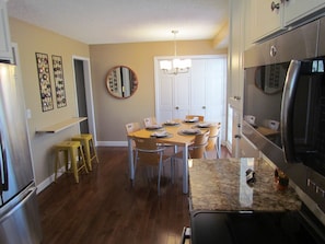 View of dining seating area, counter bar with two cute yellow stools and laundry