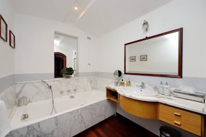 A large marble bathroom with bathtub and shower