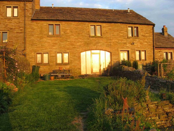 The rear of Midsummer Barn Holiday Cottage in a glorious sunset