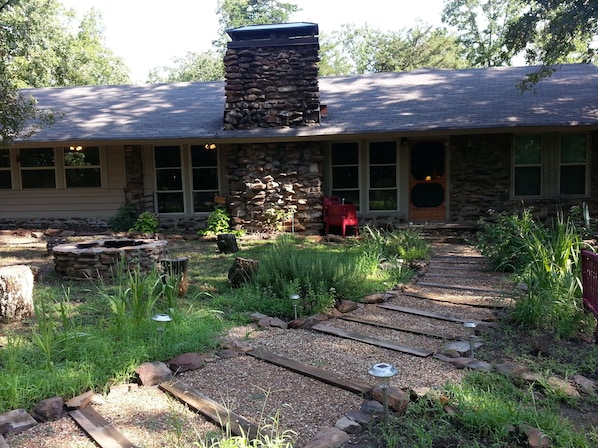 Cabin Exterior. Front herb beds and stone fire pit.
