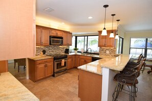 Spacious and renovated kitchen with granite countertops and dimming lights.