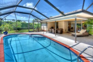 Screened-in heated pool with barbecue area.