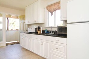 Kitchen with full size fridge, toaster oven, hot plate and microwave.