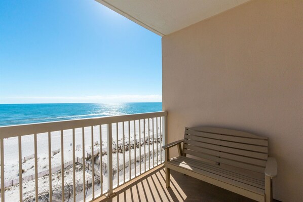 Balcony has a a bench and 2 chairs.