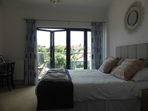 Large master bedroom with its own balcony, ensuite, large TV, dressing table.