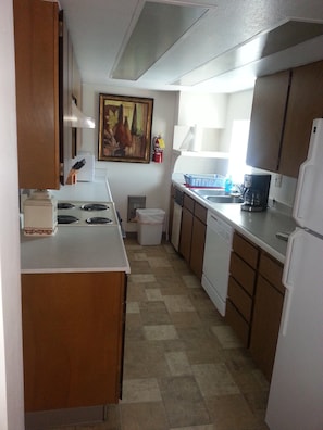 Kitchen with stove/oven, dishwasher, refrigerator and all dishes.