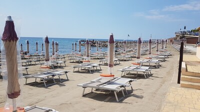 Near the sunny sea in the center with two sunbeds and an umbrella on the sand