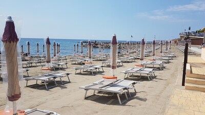 In der Nähe des sonnigen Meeres in der Mitte mit zwei Sonnenliegen und einem Sonnenschirm im Sand