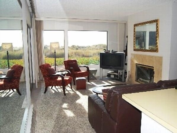 Open floorplan living room with fireplace, sweeping views & patio