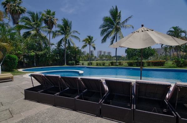 Pool area with plenty of shade, palm trees, sun loungers and wonderful views! 