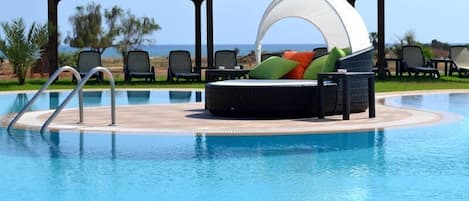 Large freeform pool with plenty of sunloungers, cabanas and other seating.