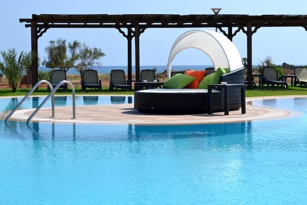 Large freeform pool with plenty of sunloungers, cabanas and other seating.