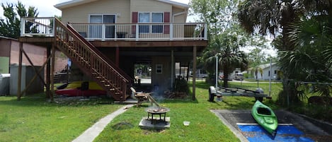 House from the dock,showing fire pit, boat/kayak launch and front deck.