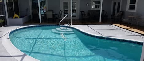 Pool looking to back porch with table to left and large seating area to right