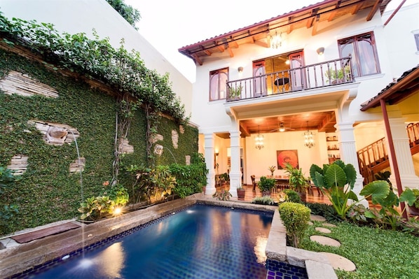 Tropical courtyard and 40' pool at dusk.  Master bedroom balcony overlooks pool