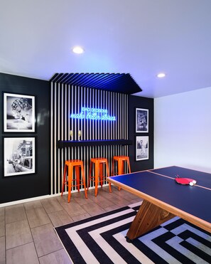 Ping pong table with custom wall bar, neon sign, and designer decor.
