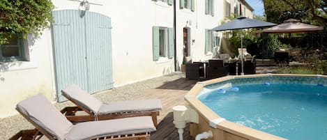 Swimming pool, front of farmhouse, seating and dining area