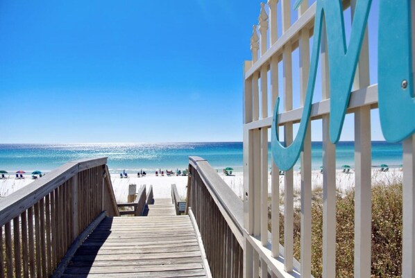 Gated private beach with a pair of chairs and umbrella