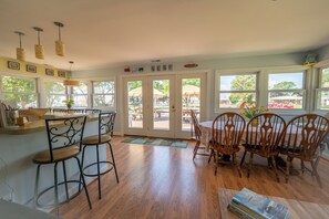 Room full of windows overlooking the large deck with propane and charcoal grills