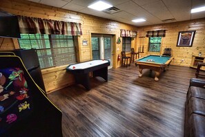 Large game room with pool table, multi-cade, air hockey, sleeper sofa and fridge