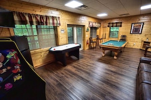 Large game room with pool table, multi-cade, air hockey, sleeper sofa and fridge