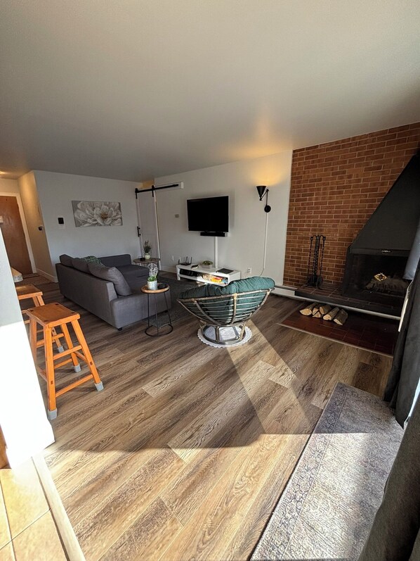 Sun filled living area with SmartTV, sound bar, wood burning fireplace, pull out