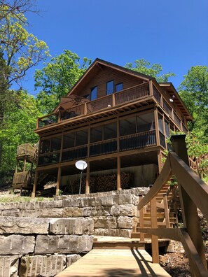 View of the back Edgewater Lodge showing the two decks and stone firepit patio.