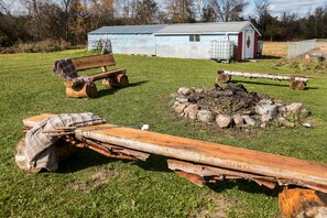 Firepit, wood on hand and utensils for roasting marshmallows and making s'mores 