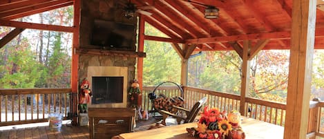 Covered deck with large tv, ceiling fans, rockers, and a view for family fun