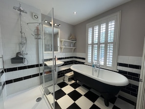 Large monochrome family bathroom with huge cast iron bath and shower.