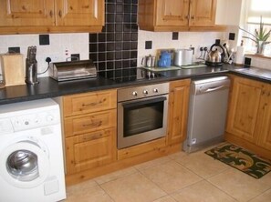 Kitchen with washing maching, cooker and dishwasher.