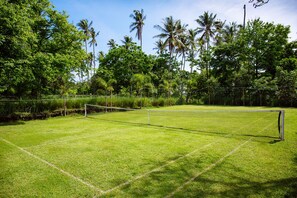 Private grass tennis court amongst lush gardens