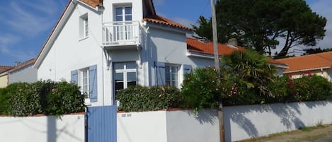 Une jolie maison avec un jardin clos de murs et fleuri de lauriers roses

  