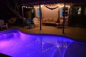 Lighted patio + deck next to heated + lighted pool and fire pit with many chairs
