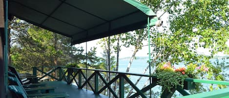 Adirondack chairs adorn the porch. The awning provides shade on hot summer days.