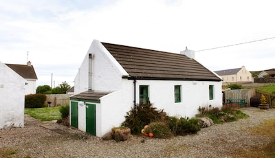 Tradicional y pequeña cabaña irlandesa encantadora con hermosas vistas al mar 