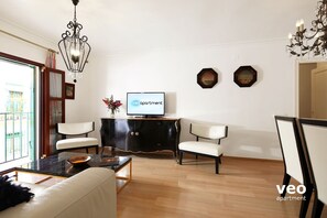 Living room furnished with sofa, 2 armchairs, coffee table and TV.