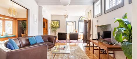 First floor living room with leather couch, smart cable TV, and Alexa speaker.